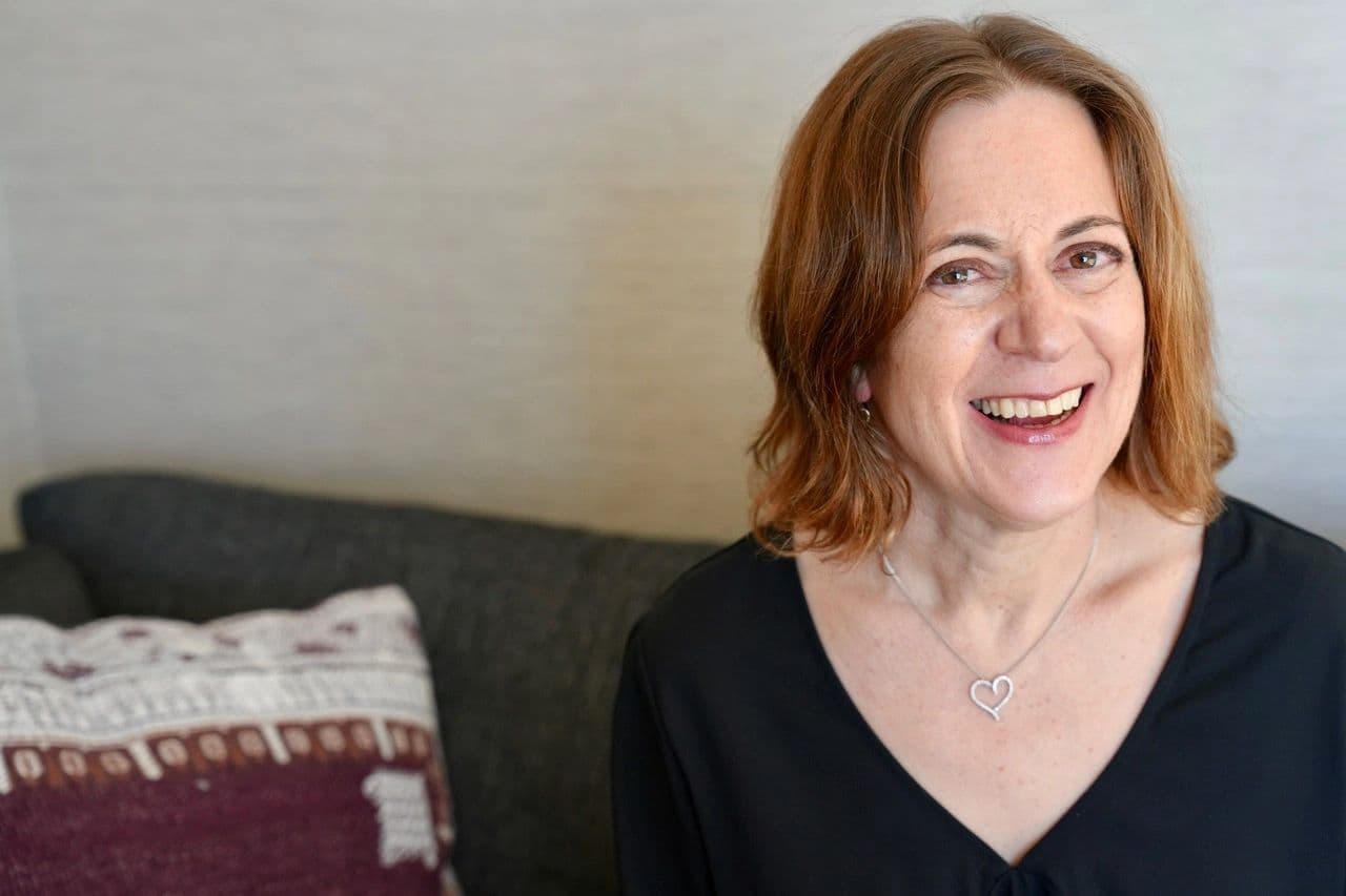 One of the two friends behind D&T Jewels — Diana and Trudy — caught mid-laugh at home, wearing one of their own silver open-heart necklaces.